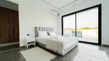 Un dormitorio moderno con una cama grande, una mesita de noche, un armario y vistas a través de un amplio ventanal.