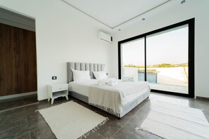 A modern bedroom with a large bed, a nightstand, a wardrobe, and a view through a large window. - 3-bedroom Villa With Private Pool Studio (Hammamet)