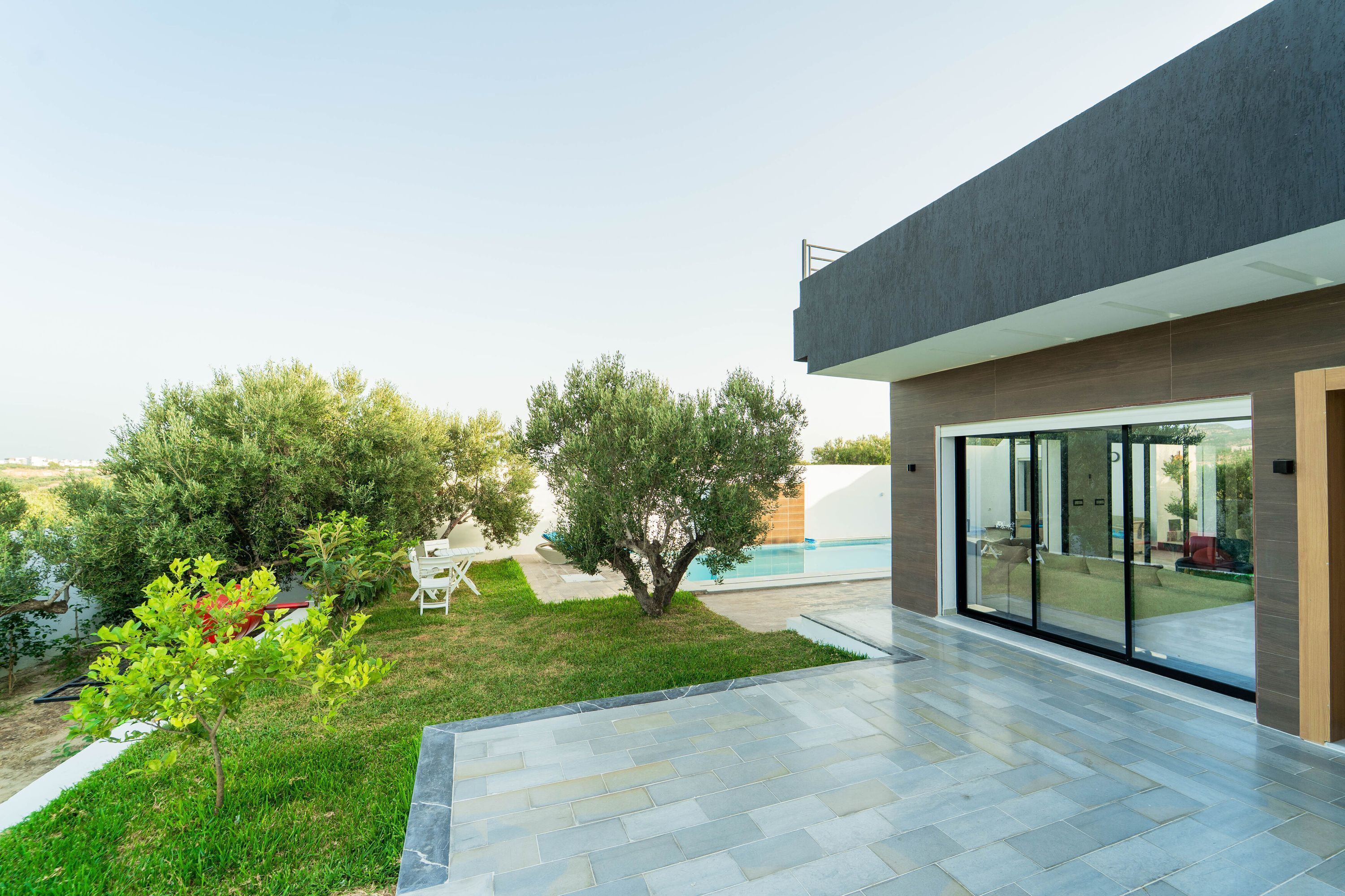 Una casa moderna con piscina, patio y jardín.