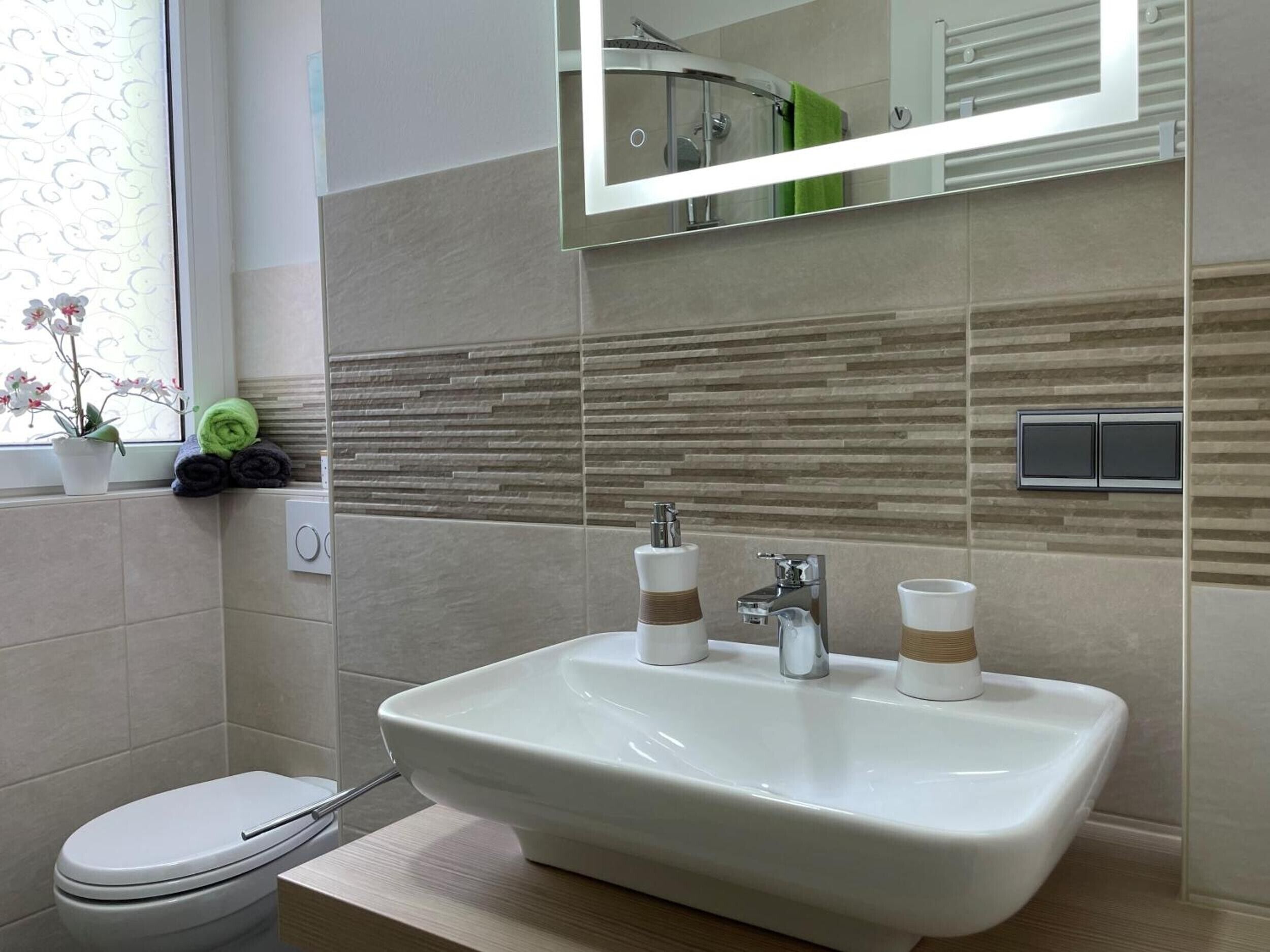 Un baño con un lavamanos blanco, dos llaves y un espejo encima.