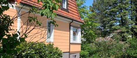 A two-story building with a red-tiled roof, white window frames, and a peach-colored facade.