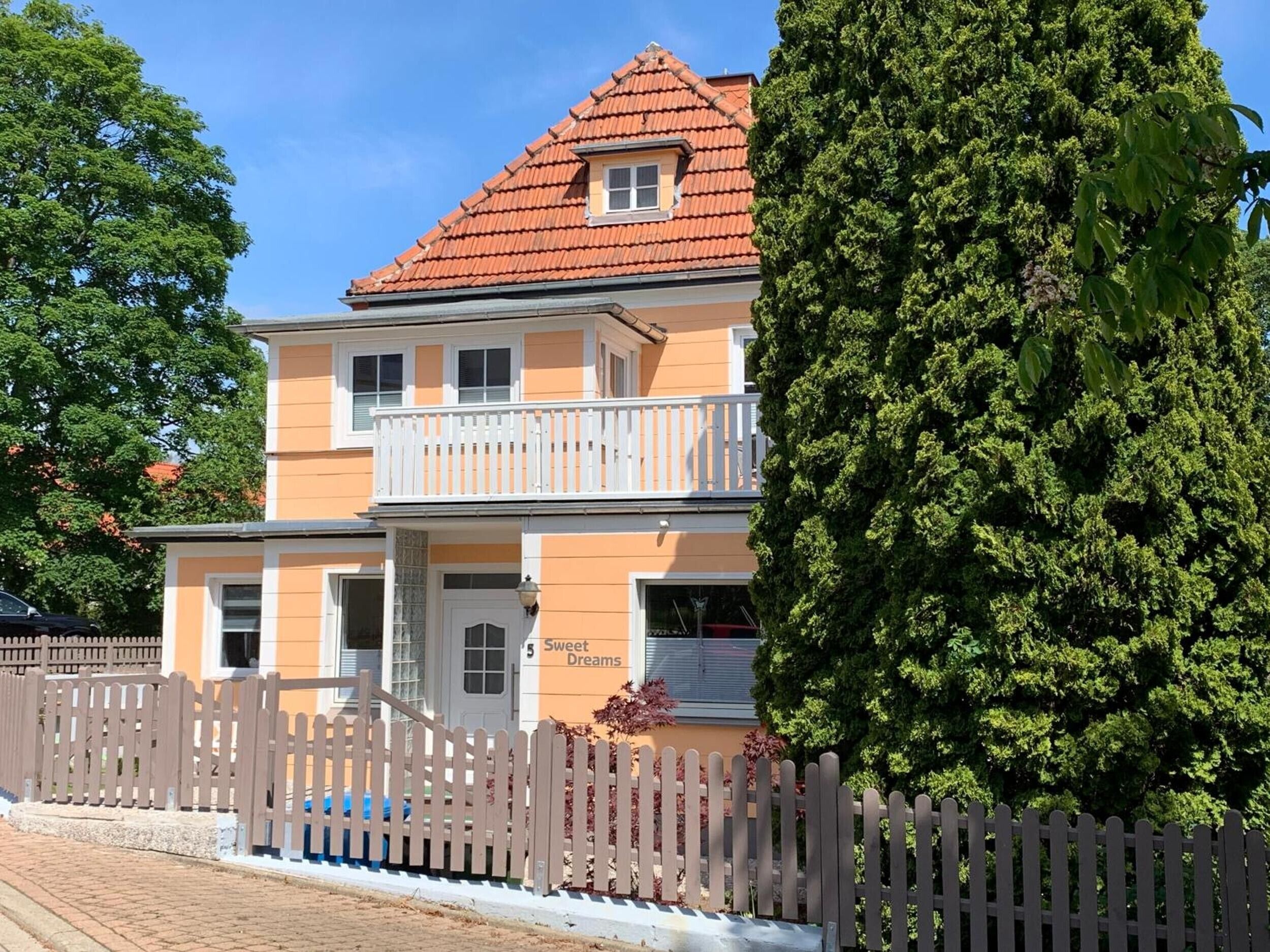 Ein zweistöckiges Gebäude mit rotem Ziegeldach, einem Balkon und einem Schild mit der Aufschrift 'Sweet Dreams'.