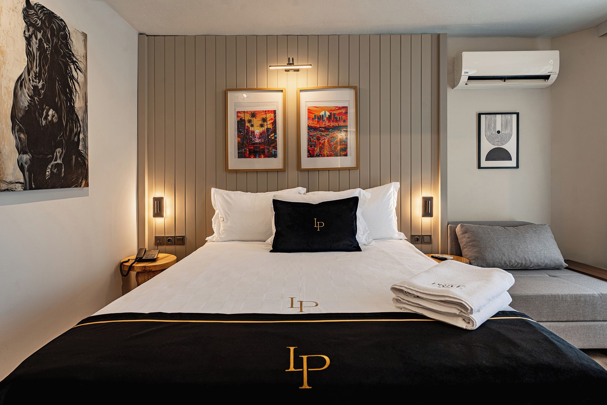 A hotel room with a bed, a nightstand, a chair, and artwork on the walls.