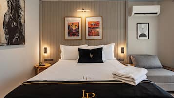 Une chambre d’hôtel avec un lit, une table de chevet, une chaise et des œuvres d’art accrochées aux murs.