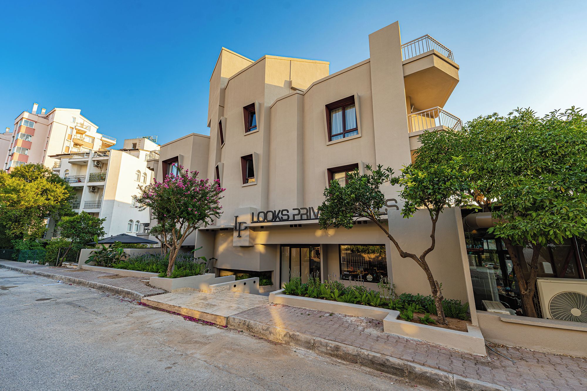 A modern building with a flat facade, multiple balconies, and a sign that reads 'LOOKS PRIV'.