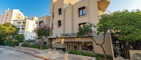 A modern building with a flat facade, multiple balconies, and a sign that reads 'LOOKS PRIV'.
