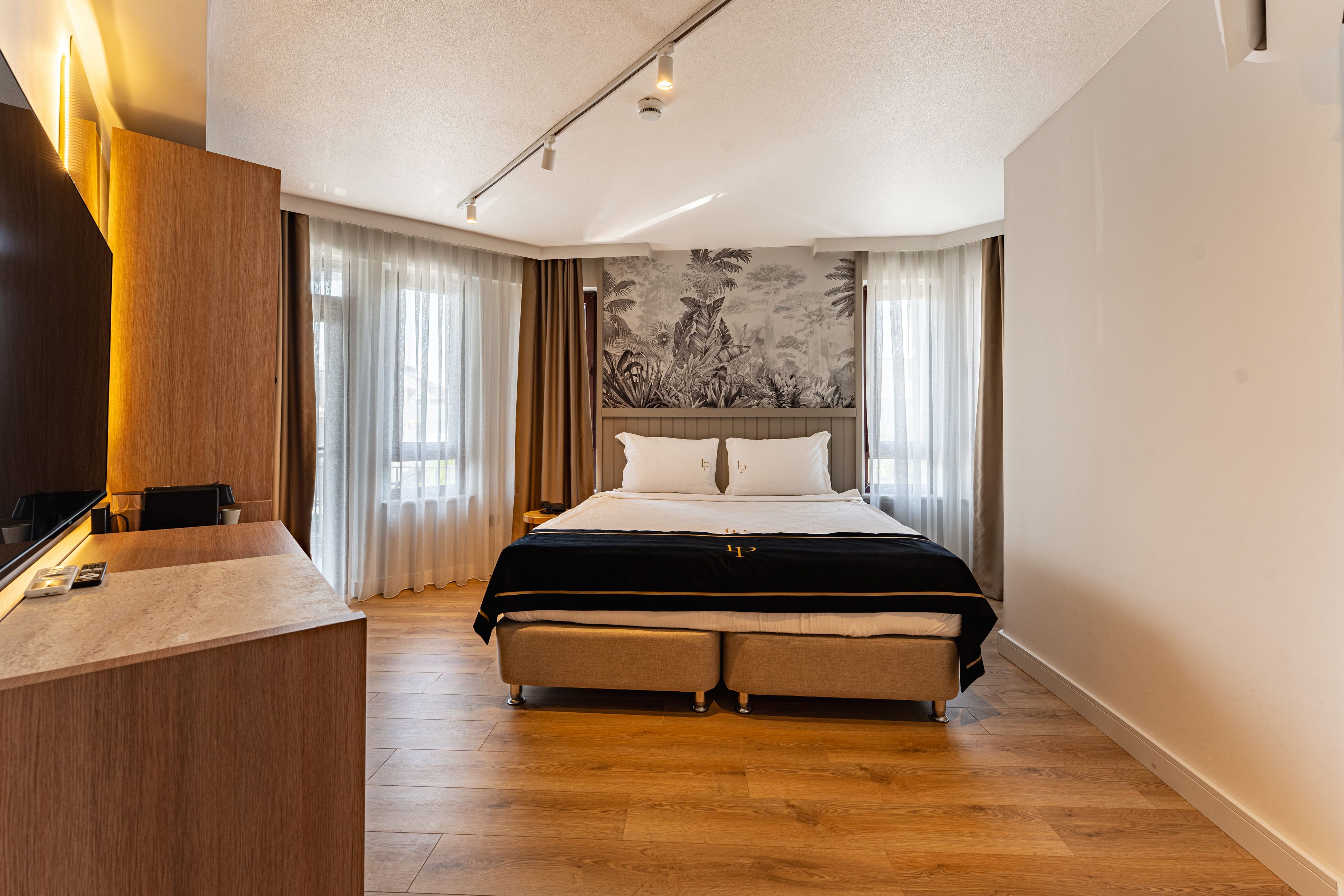 Une chambre d’hôtel moderne avec un grand lit, un bureau en bois et une fresque murale.