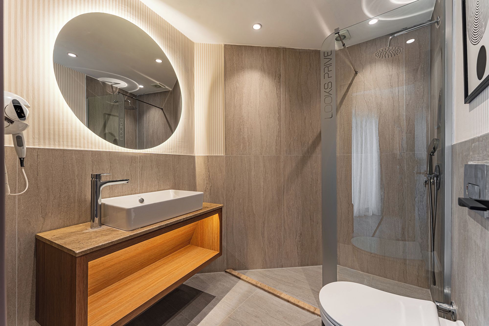 Une salle de bain moderne avec un lavabo sur pied, un miroir, un espace douche et des toilettes.