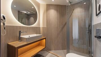Une salle de bain moderne avec un lavabo sur pied, un miroir, un espace douche et des toilettes.