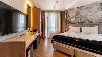 Ein Hotelzimmer mit Bett, Schreibtisch, Fernseher und einer Wand mit einem tropischen Wandbild.