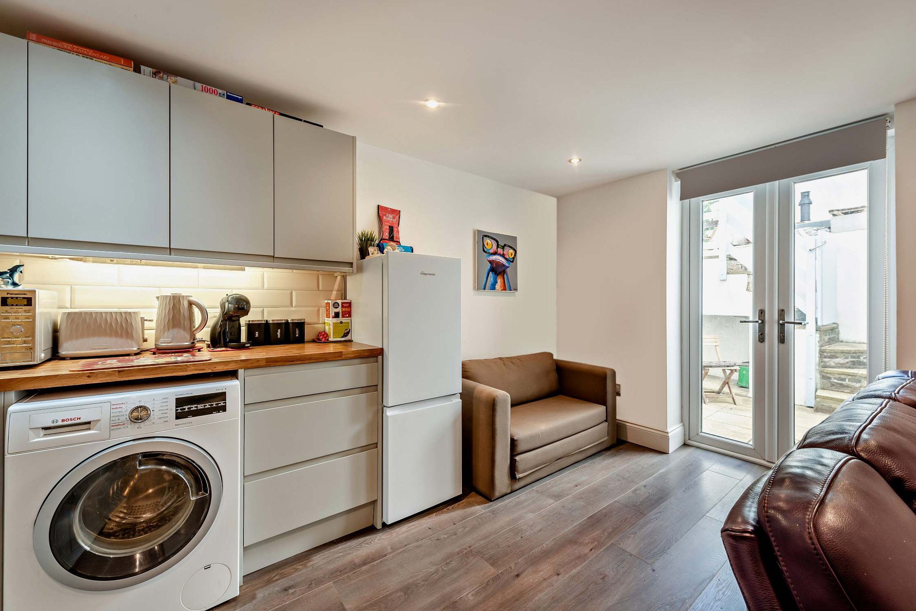 A compact kitchen with a washing machine, a refrigerator, and a dining area with a table and chairs.