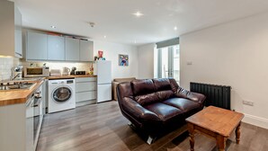 A compact living space with a kitchenette, a sofa, and a small table. - Host Stay Clarendon Violet (Brighton)