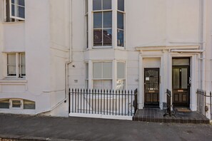 A white building with a black metal fence, a black door, and a small step leading to the entrance. - Host Stay Clarendon Violet (Brighton)