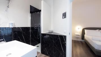 Ein modernes Badezimmer mit einem weißen Waschbecken, einer schwarzen Duschkabine aus Marmor und einer weißen Toilette.