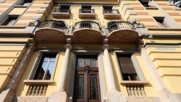 Une façade d’immeuble avec une entrée centrale, des colonnes et des balcons.