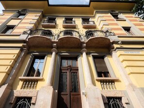 Fachada de edificio con entrada central, columnas y balcones.