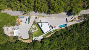 An aerial view of a property with a swimming pool, a parking lot, and a building with a flat roof. - Villa Awesome Lodge (Rasa)