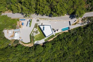 An aerial view of a property with a swimming pool, a parking lot, and a building with a flat roof. - Villa Awesome Lodge (Rasa)