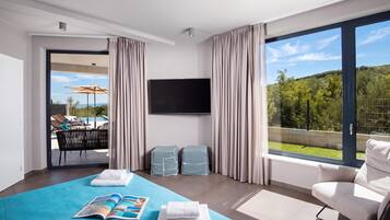 Ein modernes Hotelzimmer mit einem großen Bett, einem Flachbildfernseher und einem Balkon mit Blick auf einen Pool.