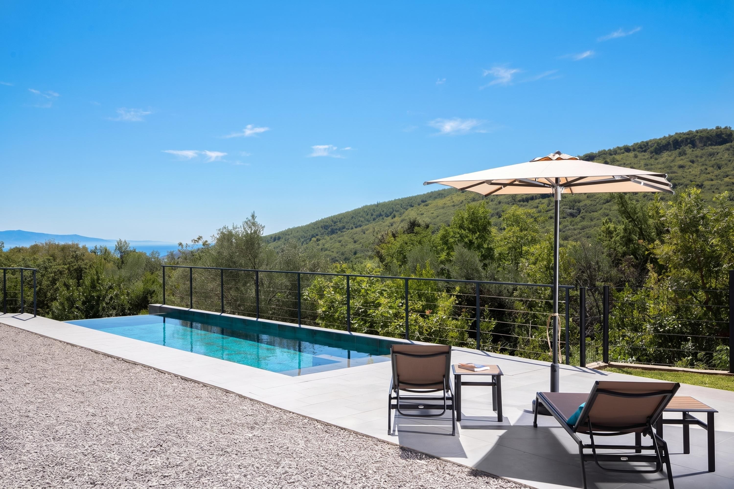 Une piscine avec vue sur une colline boisée et la mer.