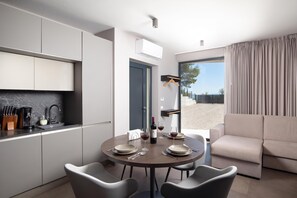 A modern kitchen with a dining area, a sofa, and a view of the outdoors. - Villa Awesome Lodge (Rasa)