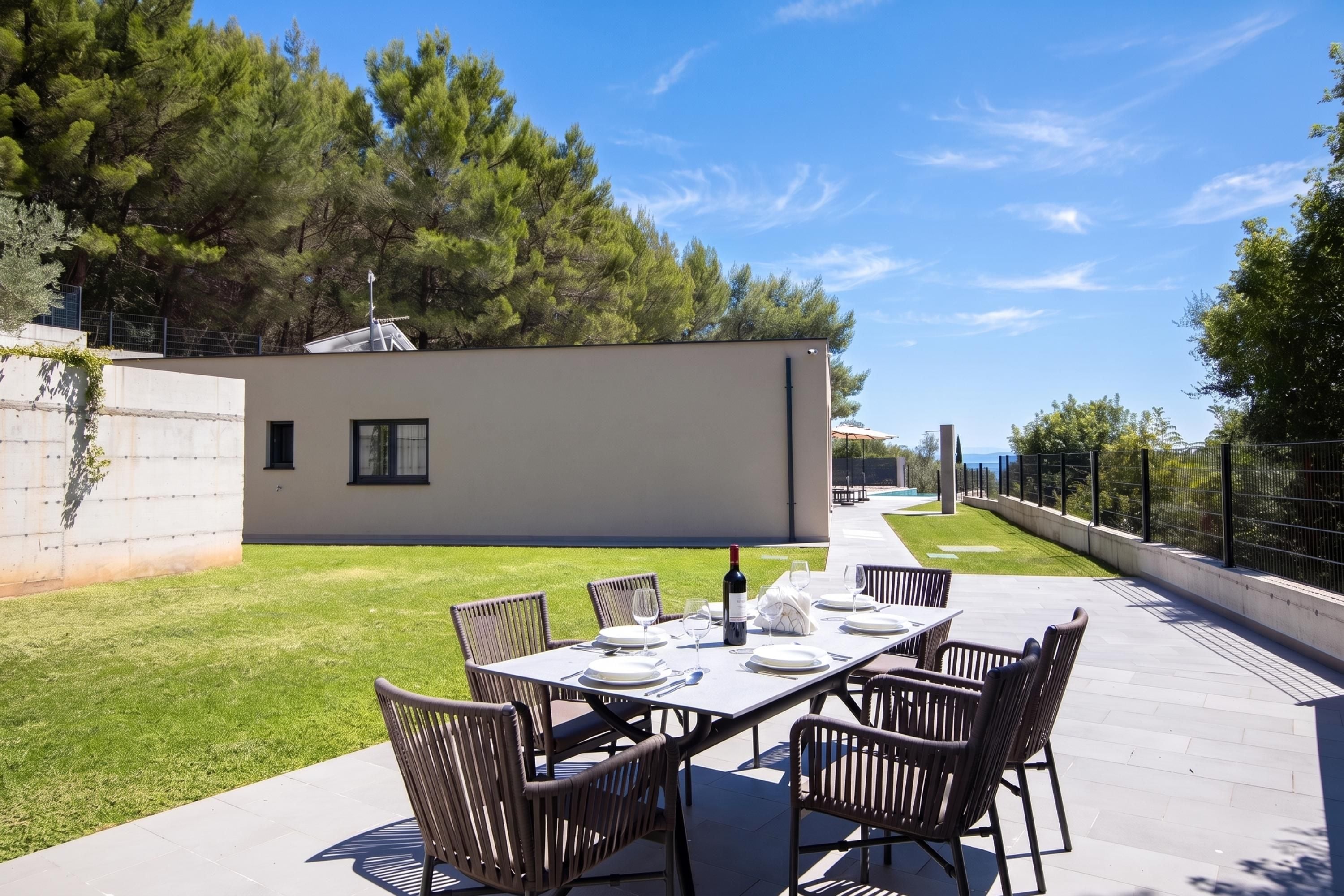 An outdoor dining area with a table set for four, surrounded by chairs, and a modern building in the background.