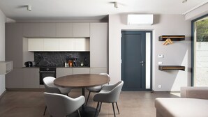 A modern kitchen with a marble countertop, a dining table with chairs, and a grey sofa in a living area. - Villa Awesome Lodge (Rasa)
