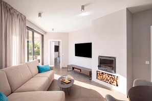 Una sala de estar moderna con un sofá, una mesa de centro, un televisor de pantalla plana y una chimenea.