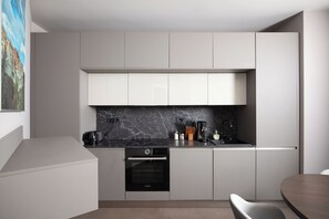 A modern kitchen with white cabinetry, a Bosch oven, and a marble backsplash. - Villa Awesome Lodge (Rasa)