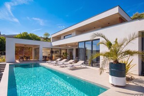 A modern house with a swimming pool, outdoor seating, and a large window overlooking the pool. - Villa Immortella Luxury Pool & Spa Retreat (Labin)