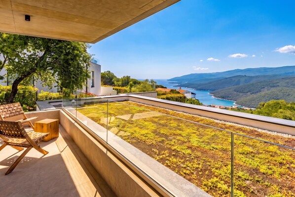 A modern outdoor seating area with a view of a coastal landscape. - Villa Immortella Luxury Pool & Spa Retreat (Labin)