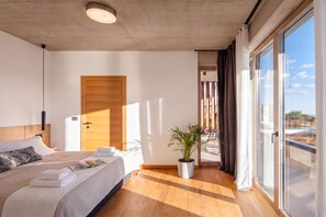 A modern hotel room with a large bed, a wooden door, a potted plant, and a view of the outdoors. - Villa Immortella Luxury Pool & Spa Retreat (Labin)