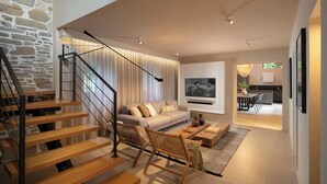 Ein modernes Wohnzimmer mit Treppe, Sofa, Couchtisch und Fernseher.