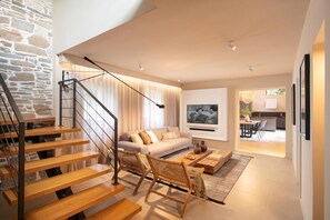 Una sala de estar moderna con una escalera, un sofá, una mesa de centro y un televisor.