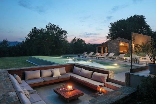 A poolside area with a built-in seating area, a stone structure, and a view of the surrounding landscape. - Villa Baracchi 4 BDR Pool Villa With Sauna in Krsan (Krsan)