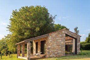 Estructura de piedra con un patio cubierto y una silla de descanso.