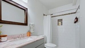 Een badkamer met een wastafelmeubel met dubbele wastafel, toilet en douche.