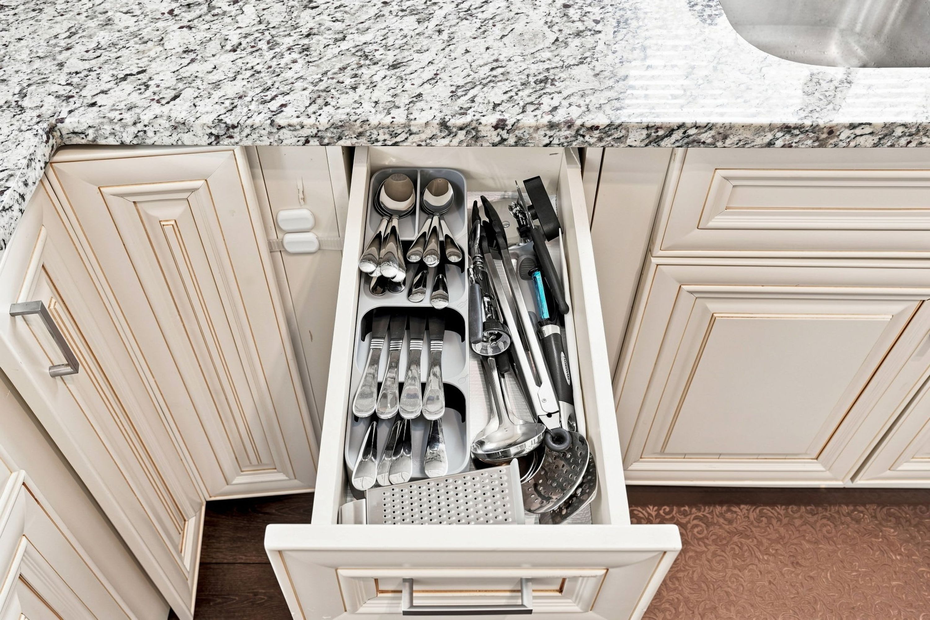 A kitchen with a drawer containing various utensils and cookware.