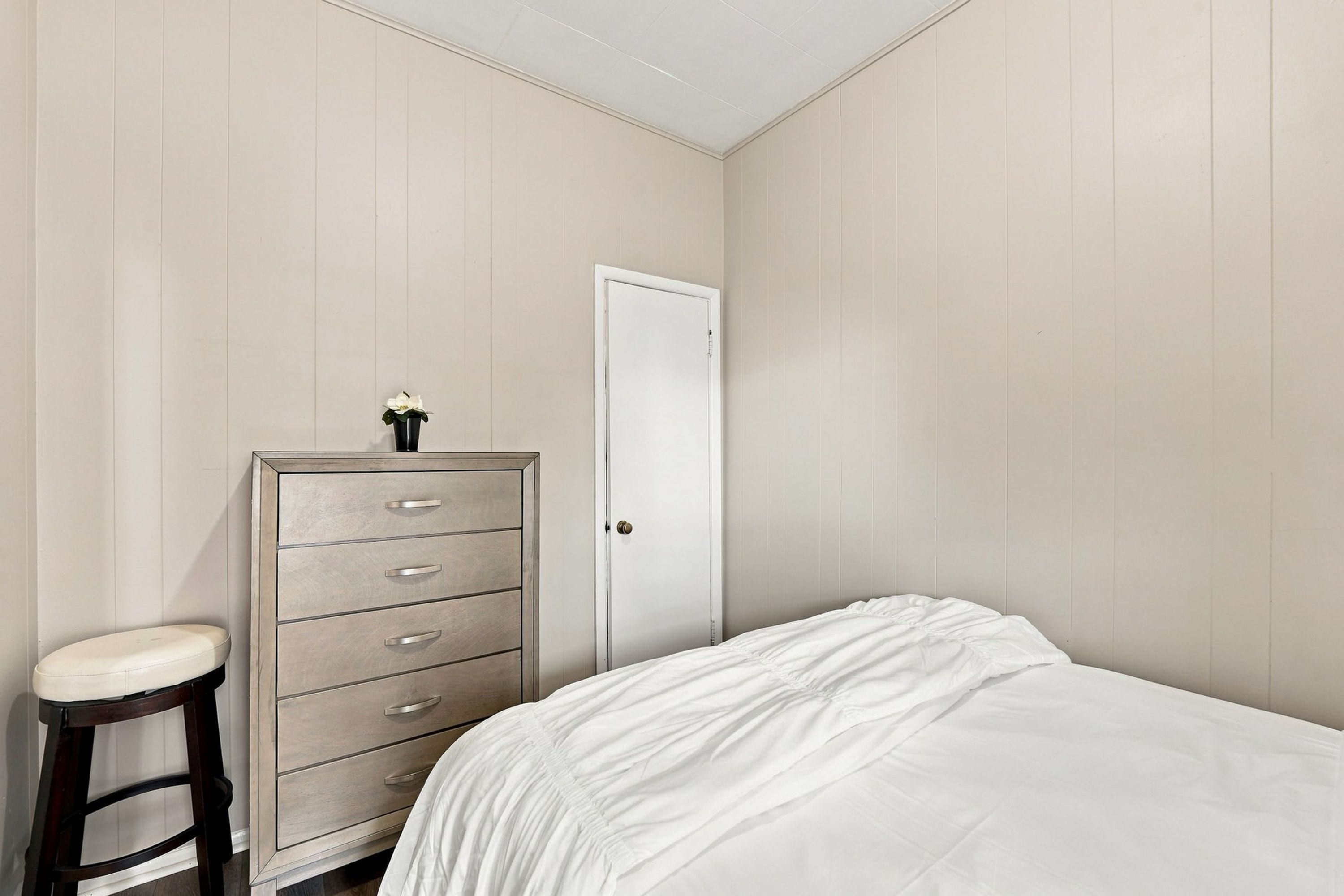 Un dormitorio con cama, cómoda y puerta.