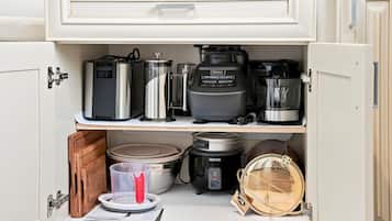 Un mueble de cocina con varios electrodomésticos, incluyendo una cafetera, una cocedora de arroz y una olla de cocción lenta.