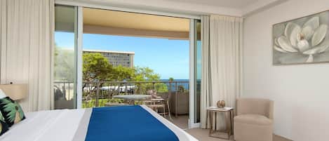 Ein Hotelzimmer mit Bett, einem Sessel, einem kleinen Tisch und Blick ins Freie.
