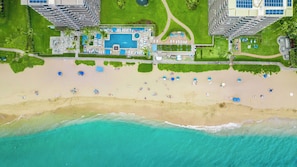 An aerial view of a resort with a large pool, beach, and high-rise buildings. - Whaler | 2 Oceanfront Villas, Sleeps 4 | Car Incl. w/ 6+ Nights | ML-4187 by KBM (Lahaina)