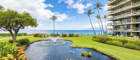 A hotel with a pool, palm trees, and a view of the ocean.
