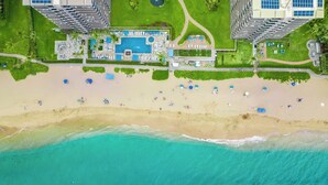 Vista aérea de un resort con una piscina grande, playa y edificios altos.