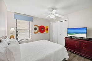 Ein Hotelzimmer mit einem Bett, einem Deckenventilator, einem Fernseher und einer Wand mit abstrakter Kunst.