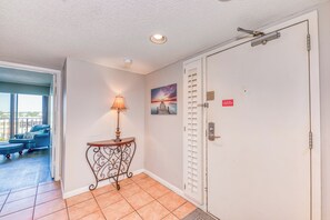 A hotel room with a door, a window, a lamp, a picture on the wall, and a view of the outside. - Phoenix II 2031 by Liquid Life (Orange Beach)