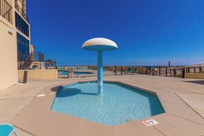 A rooftop pool with a central water feature, surrounded by lounge chairs and a clear view of the ocean. - Phoenix II 2031 by Liquid Life (Orange Beach)