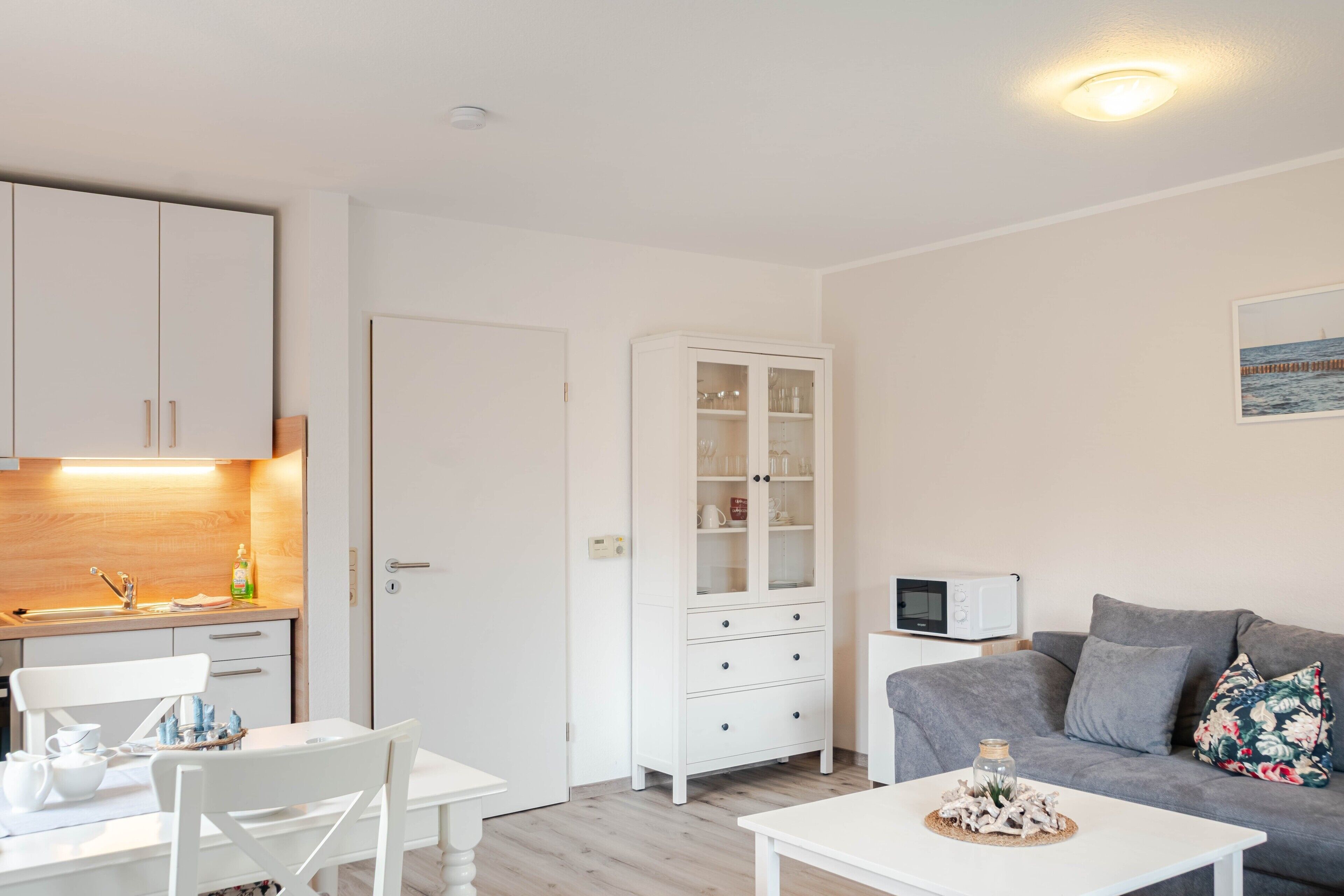 Ein kompakter Wohnraum mit Küchenzeile, einem Essbereich und einer Sitzecke mit Sofa und Couchtisch.