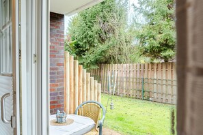 Eine Terrasse mit Tisch und Stühlen, ein Holzzaun und eine Backsteinmauer.