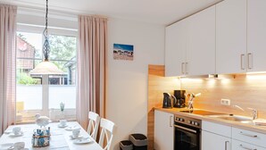 Et moderne køkken med hvide skabe, en træbordplade og en spiseplads med et bord dækket til fire personer.